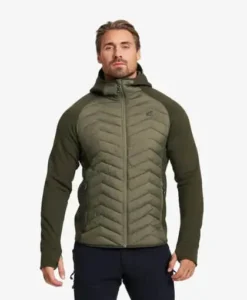 Mies vihreässä hybridifleece-takissa vaalealla taustalla.