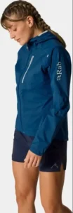 Nainen sinisessä Rab Women’s Downpour Trail Light Jacket -kuoritakissa.