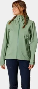 Nainen vihreässä Rab Women’s Firewall Light Jacket -kuoritakissa.